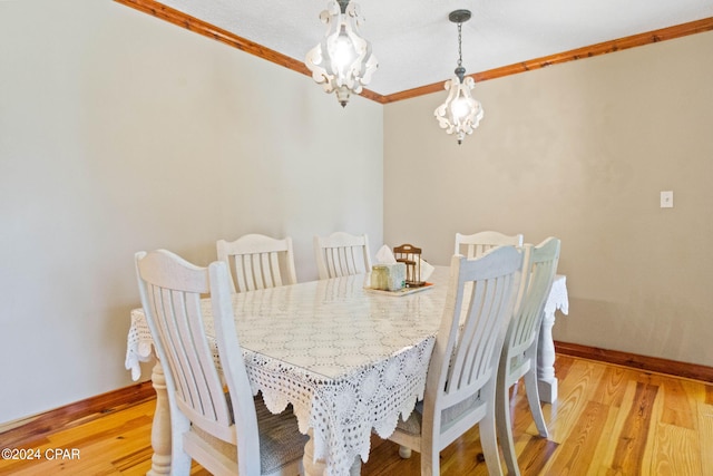 dining space featuring a notable chandelier, light wood-type flooring, and crown molding