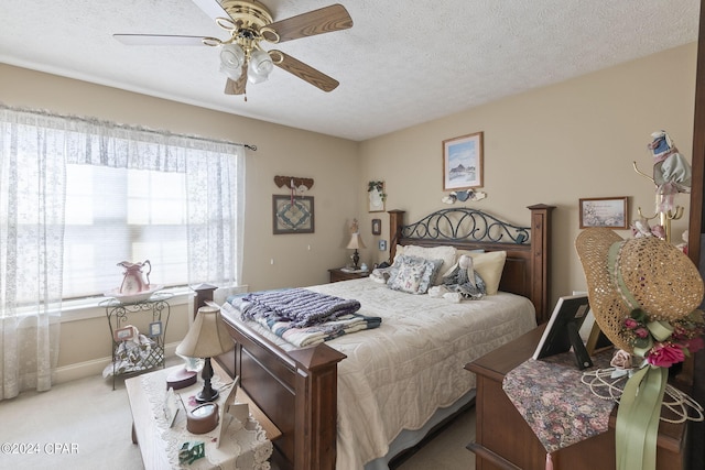 bedroom featuring a textured ceiling, light colored carpet, and ceiling fan