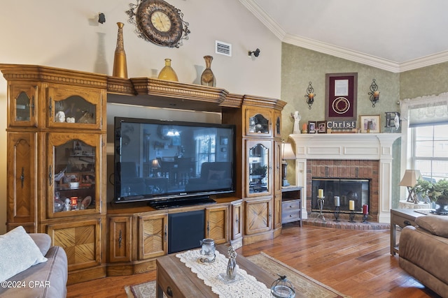 living room with hardwood / wood-style floors, crown molding, lofted ceiling, and a fireplace