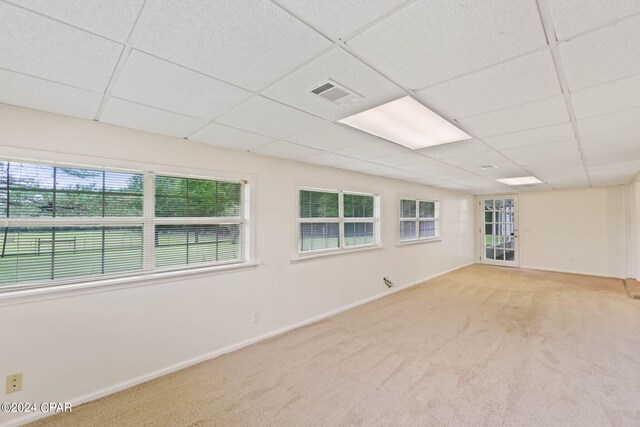 spare room featuring a paneled ceiling and light carpet