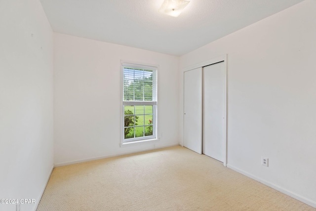 unfurnished bedroom with light colored carpet and a closet