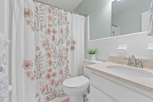 bathroom featuring tasteful backsplash, tile walls, vanity, and toilet