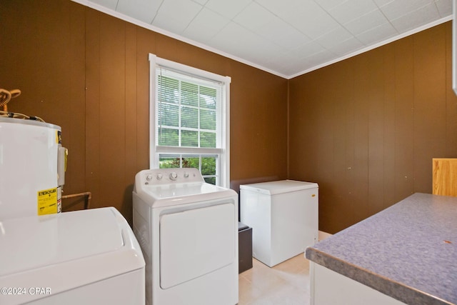 laundry area featuring wood walls, water heater, crown molding, and washer and clothes dryer