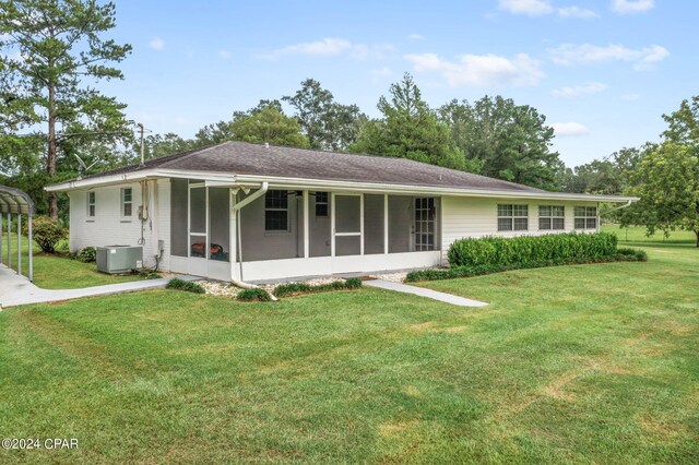 ranch-style home with a front yard, a sunroom, and cooling unit