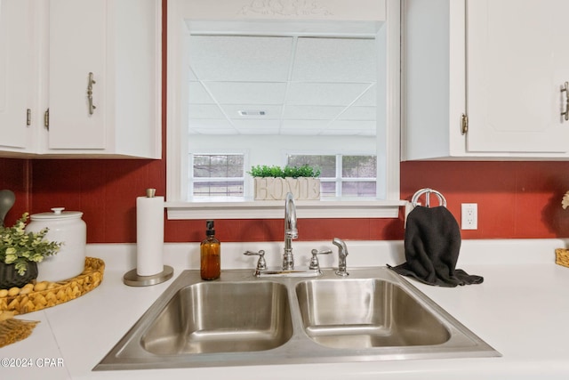 kitchen featuring a paneled ceiling, sink, and white cabinets