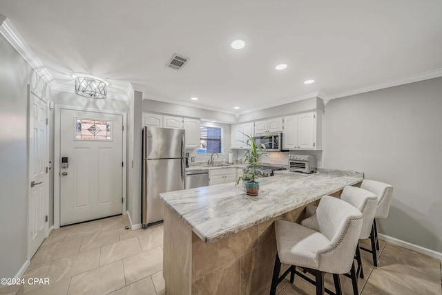 kitchen featuring a kitchen bar, kitchen peninsula, white cabinetry, and appliances with stainless steel finishes