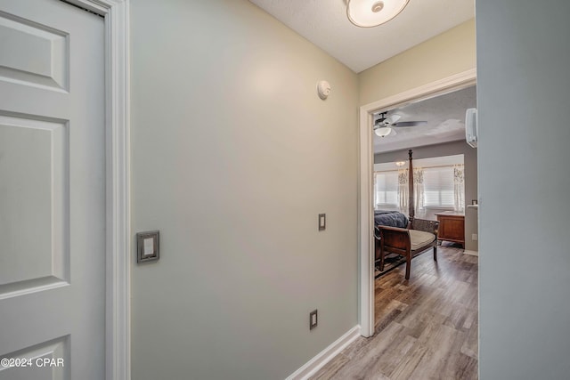 corridor featuring light hardwood / wood-style floors and a textured ceiling