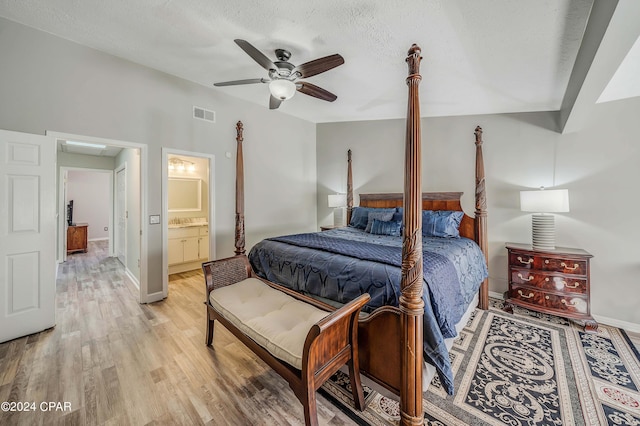 bedroom with ensuite bath, ceiling fan, a textured ceiling, and light wood-type flooring