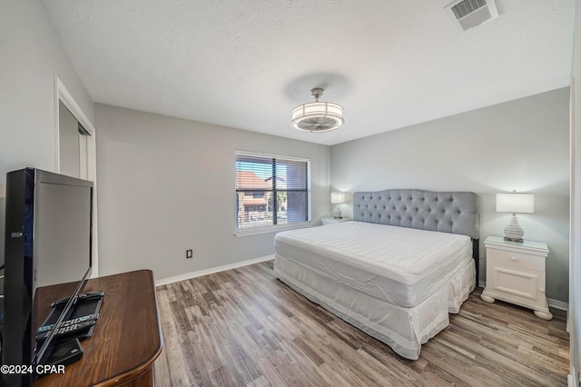 bedroom with wood-type flooring and a textured ceiling