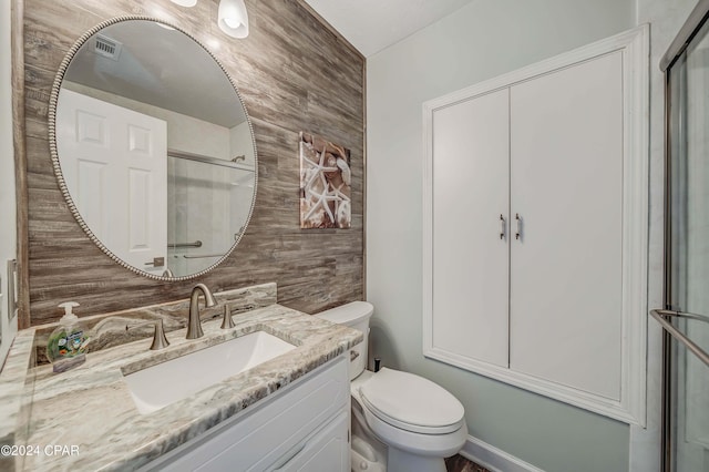 bathroom with a shower with door, vanity, and toilet