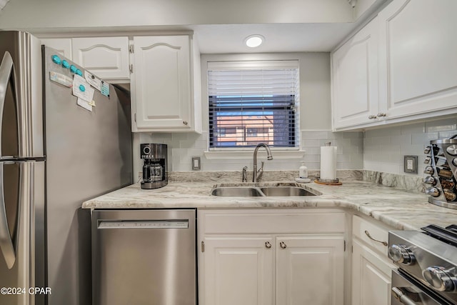 kitchen featuring sink, decorative backsplash, appliances with stainless steel finishes, light stone counters, and white cabinetry