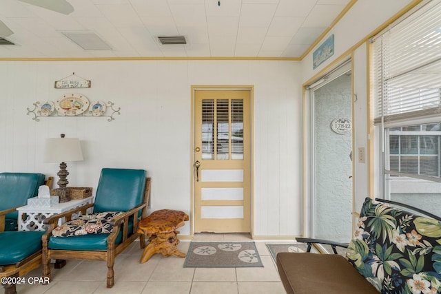 interior space featuring light tile patterned flooring, wooden walls, and crown molding