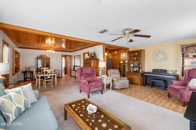 carpeted living room with ceiling fan, plenty of natural light, wood walls, and crown molding