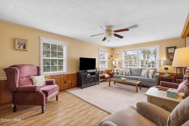 living room with ceiling fan, light hardwood / wood-style flooring, wood walls, and ornamental molding