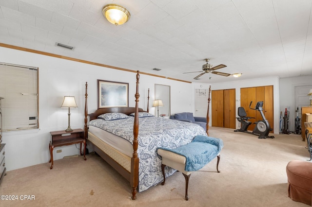 bedroom featuring two closets, ornamental molding, light carpet, and ceiling fan