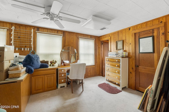 carpeted office with ceiling fan and wooden walls