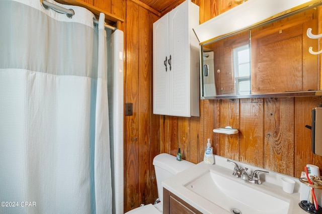 bathroom with vanity, wooden walls, toilet, and curtained shower