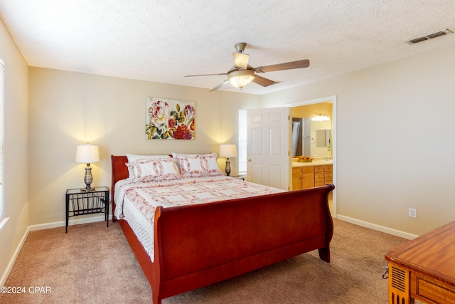 bedroom featuring ceiling fan, connected bathroom, a textured ceiling, and light carpet