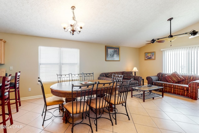 tiled dining space with ceiling fan with notable chandelier, a textured ceiling, and vaulted ceiling