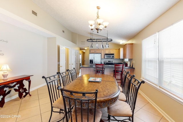 tiled dining space featuring a notable chandelier and lofted ceiling