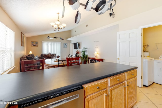 kitchen featuring washer and dryer, vaulted ceiling, dishwasher, and a healthy amount of sunlight