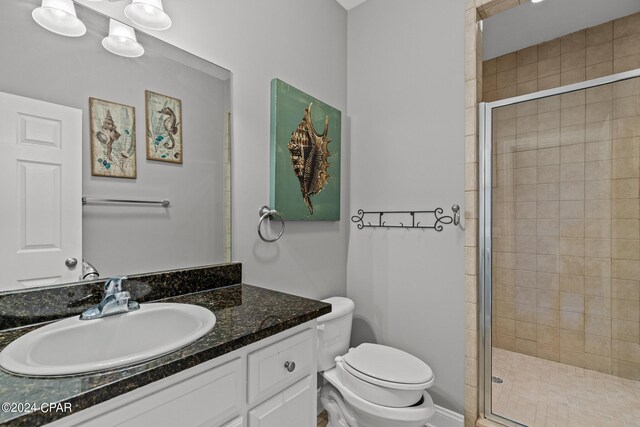 bathroom with a shower with shower door, vanity, and toilet