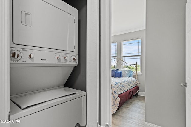 clothes washing area featuring stacked washer and dryer and light wood-type flooring