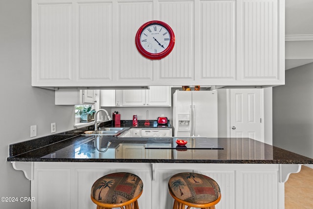 kitchen featuring kitchen peninsula, a kitchen bar, sink, light tile flooring, and white refrigerator with ice dispenser