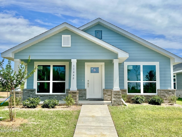 view of front of home with covered porch and a front lawn