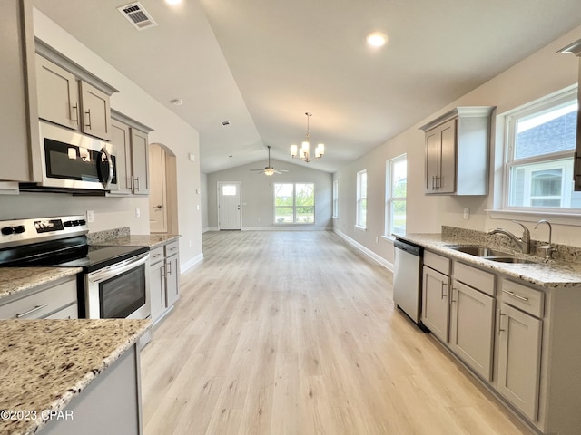 kitchen with appliances with stainless steel finishes, ceiling fan with notable chandelier, vaulted ceiling, sink, and light hardwood / wood-style flooring