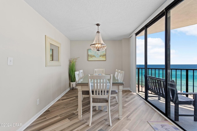 dining area featuring a water view, a chandelier, wood-type flooring, and floor to ceiling windows