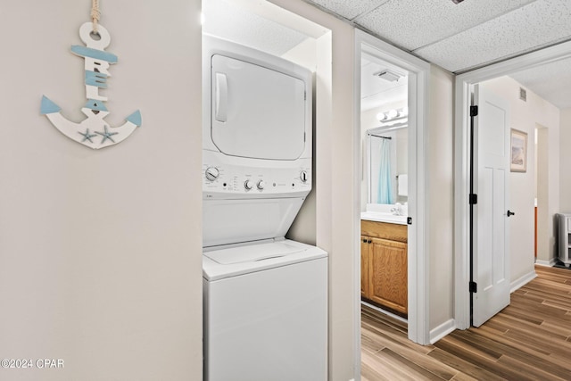 laundry room featuring hardwood / wood-style flooring and stacked washer and dryer