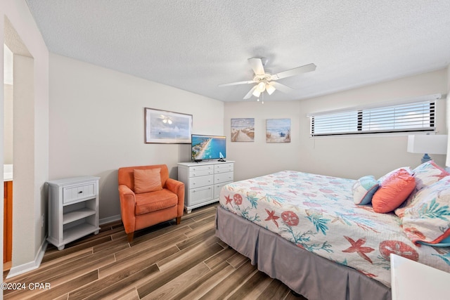 bedroom with ceiling fan, dark wood-type flooring, and a textured ceiling