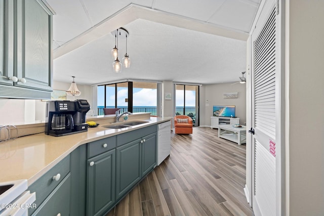 kitchen with decorative light fixtures, ceiling fan, dishwasher, light hardwood / wood-style floors, and sink