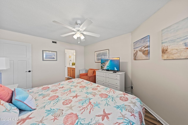 bedroom with a textured ceiling, ceiling fan, ensuite bathroom, and hardwood / wood-style floors