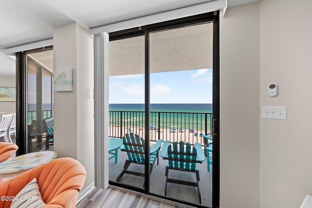 doorway featuring floor to ceiling windows, light hardwood / wood-style floors, a textured ceiling, and a water view