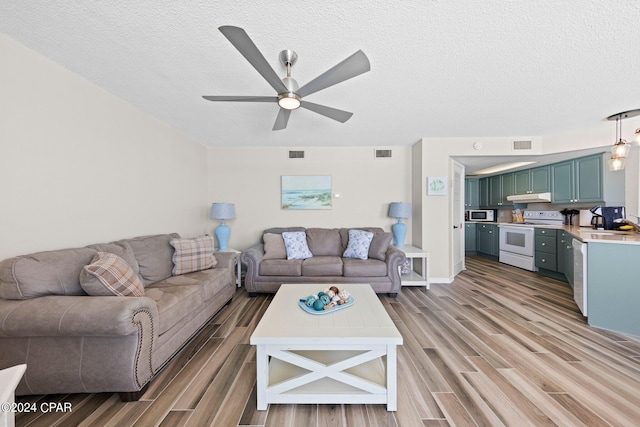 living room with ceiling fan, sink, a textured ceiling, and hardwood / wood-style floors