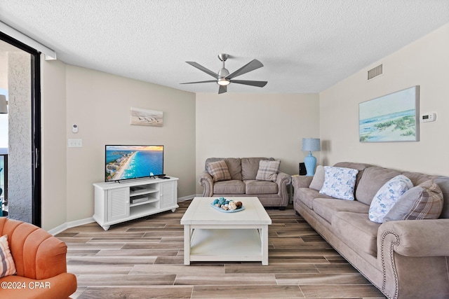 living room featuring ceiling fan, a textured ceiling, and hardwood / wood-style floors