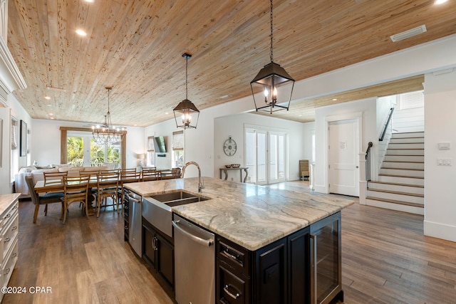 kitchen featuring an inviting chandelier, stainless steel dishwasher, a kitchen island with sink, hardwood / wood-style floors, and decorative light fixtures