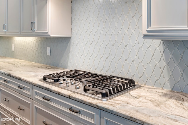 kitchen with light stone countertops, tasteful backsplash, and stainless steel gas cooktop