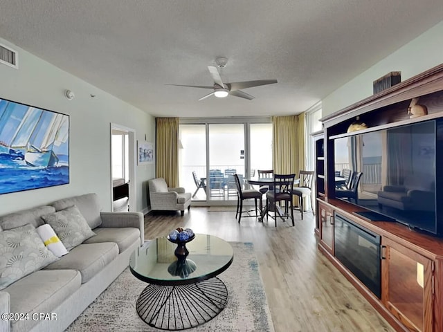 living room featuring ceiling fan, hardwood / wood-style flooring, floor to ceiling windows, and a textured ceiling