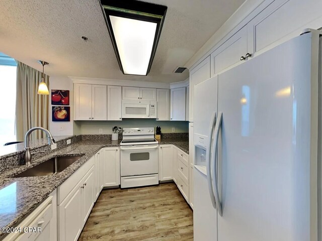 kitchen with white appliances, dark stone countertops, light hardwood / wood-style floors, white cabinetry, and sink