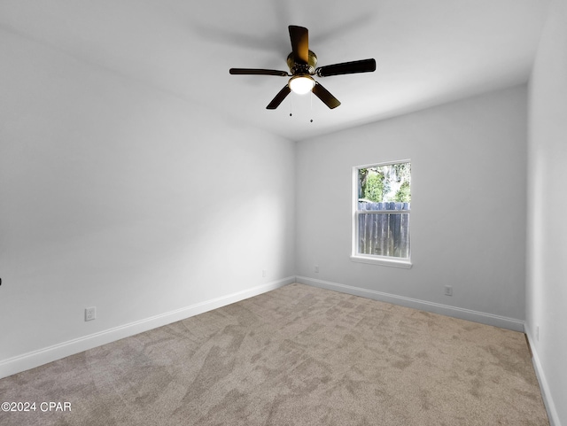 carpeted empty room featuring a ceiling fan and baseboards