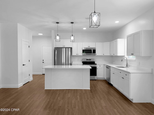 kitchen with stainless steel appliances, sink, decorative light fixtures, a kitchen island, and dark wood-type flooring