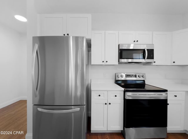 kitchen featuring baseboards, dark wood-style floors, appliances with stainless steel finishes, light countertops, and white cabinetry