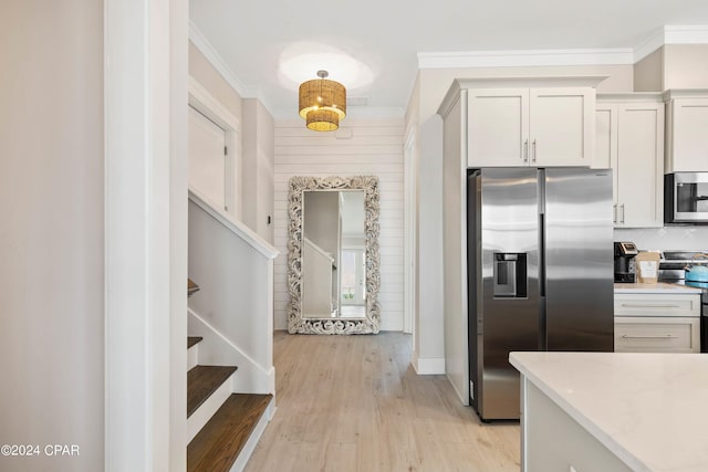 kitchen featuring white cabinets, light hardwood / wood-style flooring, ornamental molding, appliances with stainless steel finishes, and light stone counters