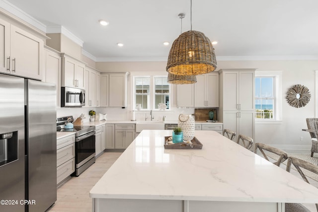 kitchen with light stone countertops, appliances with stainless steel finishes, a center island, and decorative light fixtures