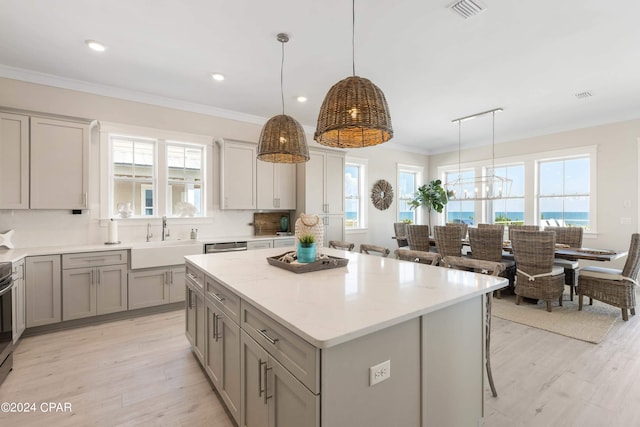 kitchen featuring a center island, decorative light fixtures, light hardwood / wood-style floors, and sink