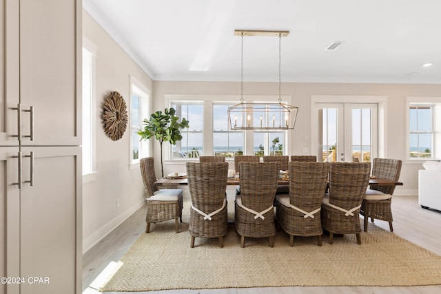 dining space with hardwood / wood-style floors, french doors, plenty of natural light, and a notable chandelier