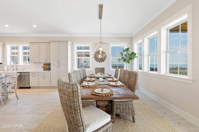 dining space featuring a chandelier, light wood-type flooring, and crown molding